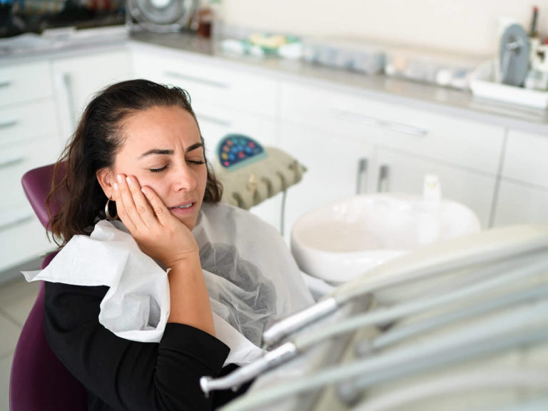 a woman holding her cheek in pain