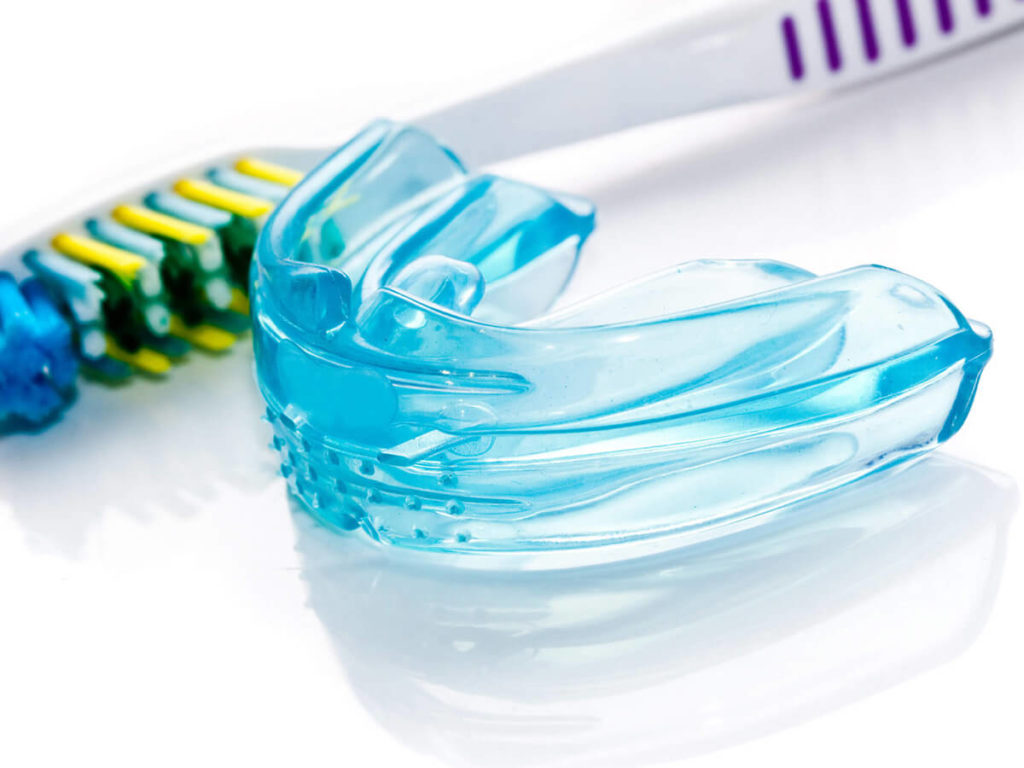 a blue mouth guard and tooth on a white background