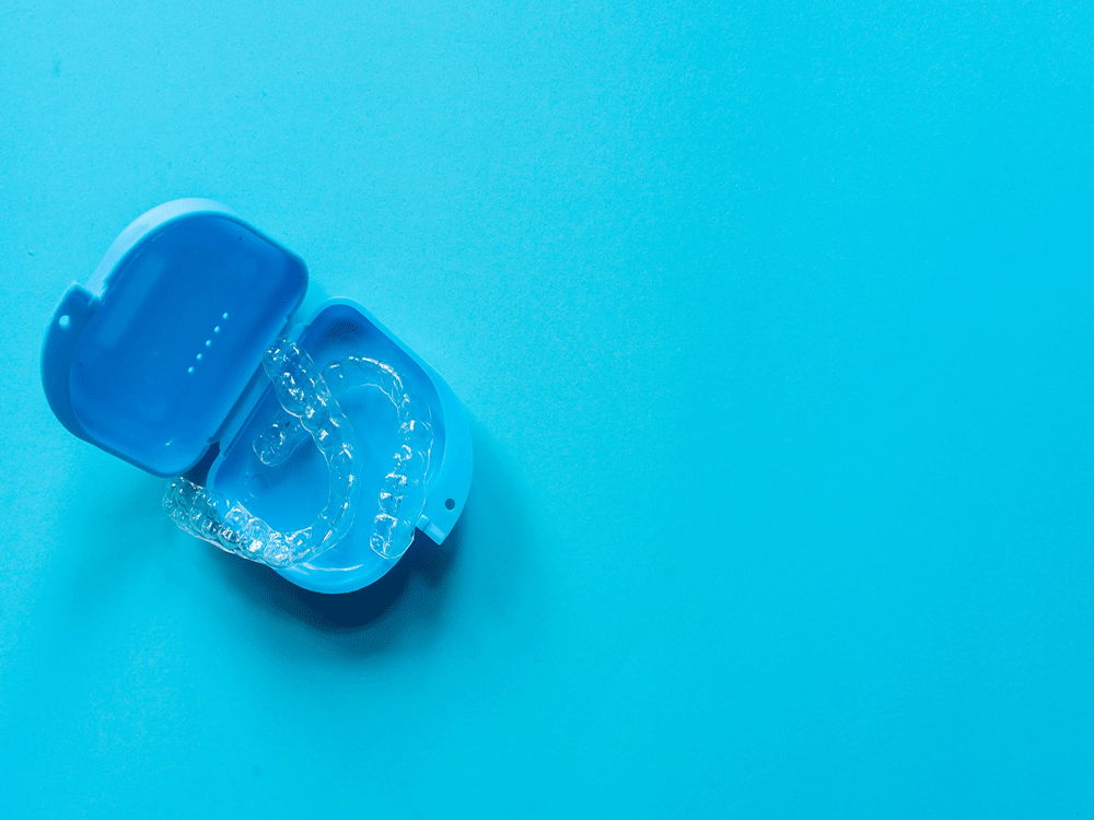 a set of clear aligners in a blue travel case on an aqua blue background